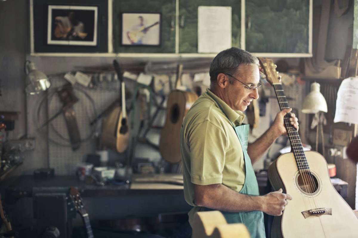 Luthier inspecting an acoustic guitar in a workshop