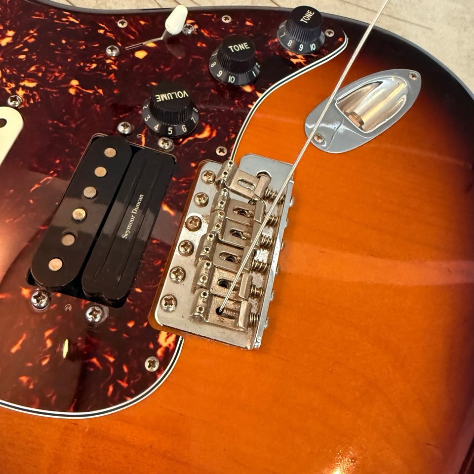 Seymour Duncan bridge pickup beside the six-screw tremolo bridge on Nick's Strat during a string change